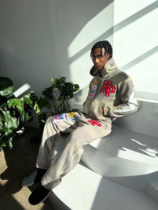 customer in the full ash k1 tracksuit sitting on white steps in hard sunlight