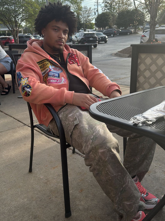 customer in the peach k1 zip up and camo cargos sitting at an outdoor table