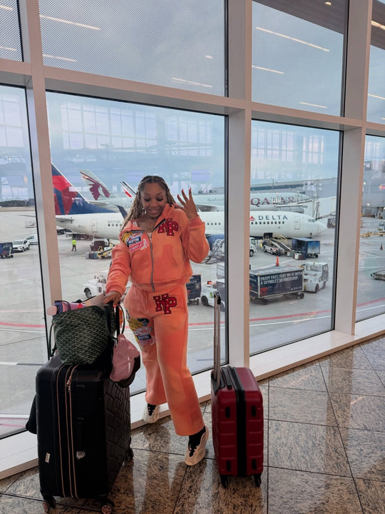 customer in the full peach k1 tracksuit at an airport gate with luggage